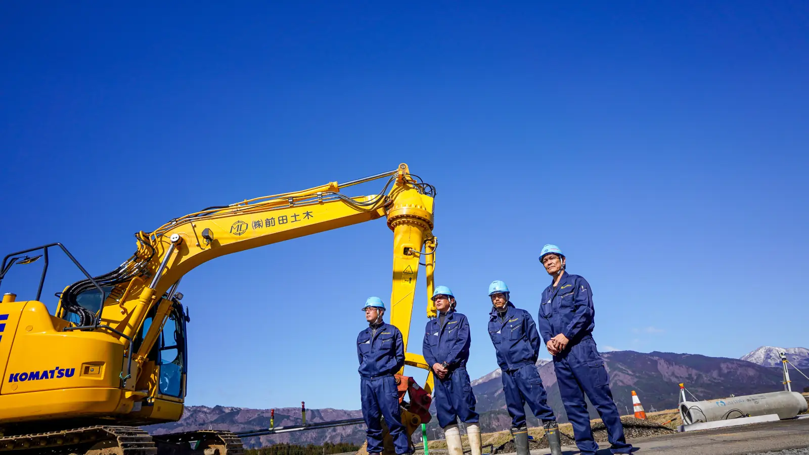 撮影例:重機の前に並ぶ建設会社の社員